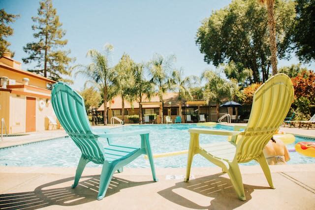 Two chairs and tall trees around the Cranbrook pool.
